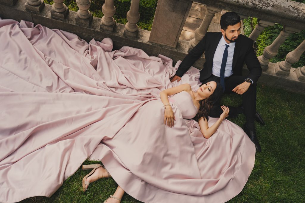 Woman lying on green grass in a blush pink long train dress